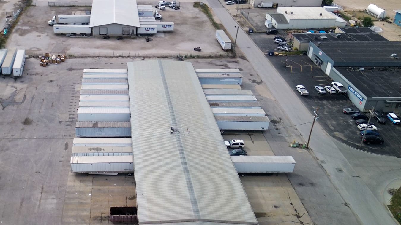 Aerial view of dry van trailers backed into the dock doors of a distribution warehouse.